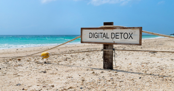 Old wooden sign with text digital detox on tropical beach. Rest from social media gadget and internet
