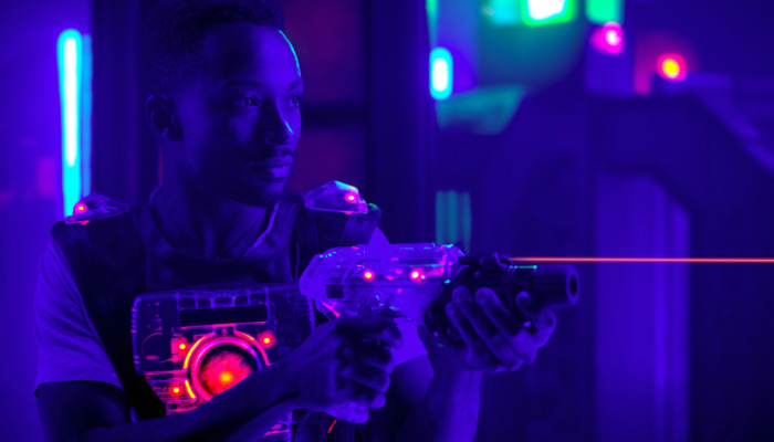 laser tag player holding gun shooting light in black light labyr
